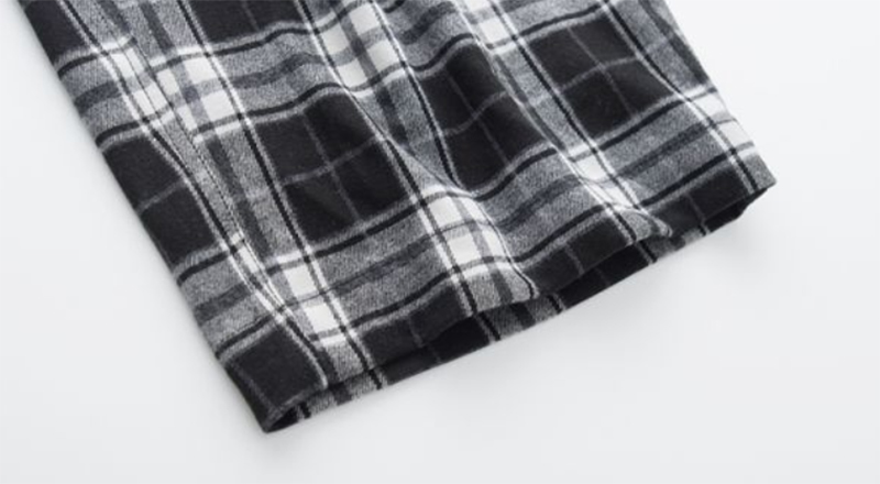 Détail bas du pantalon large à carreaux écossais femme en tissu gris, noir et blanc avec motif tartan