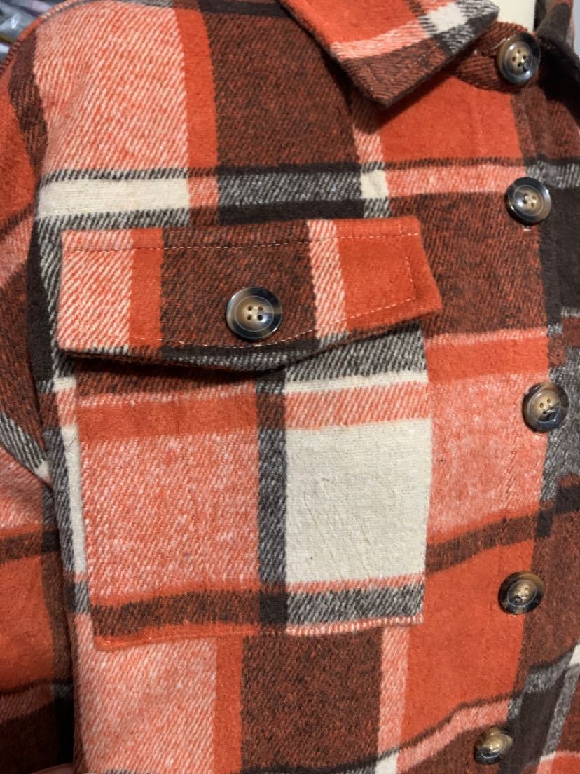 Détail de la poche à rabat boutonnée du manteau long écossais orange en tissu tartan