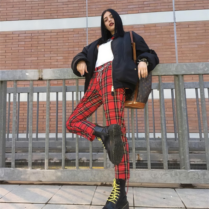 Pantalon femme en tissu tartan écossais rouge à carreaux, coupe ajustée, porté avec bottines noires à lacets jaunes