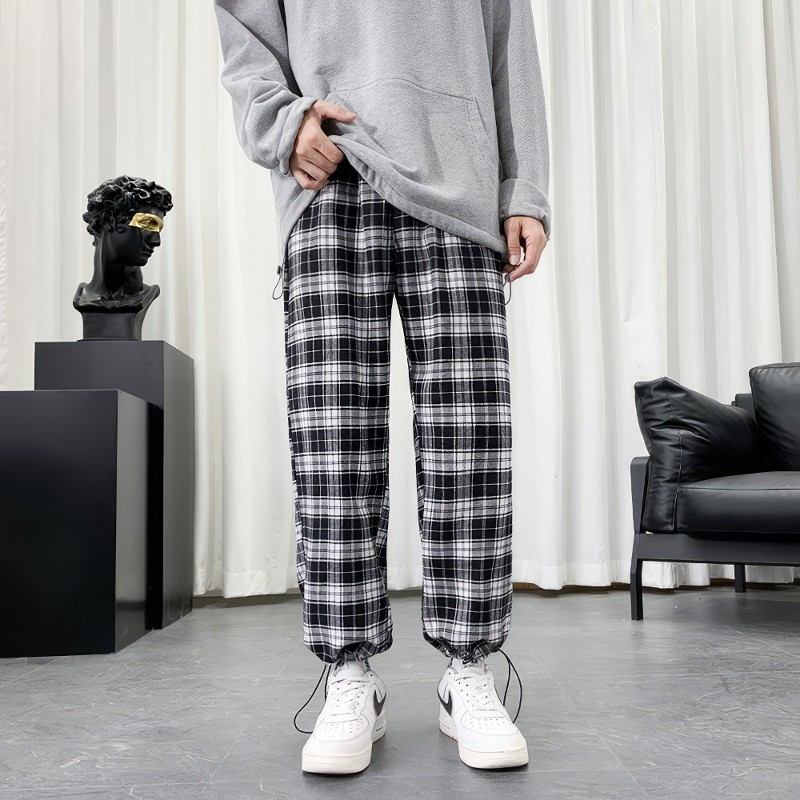 Pantalon écossais à carreaux noir et blanc avec bas resserré porté avec sweat gris et baskets blanches