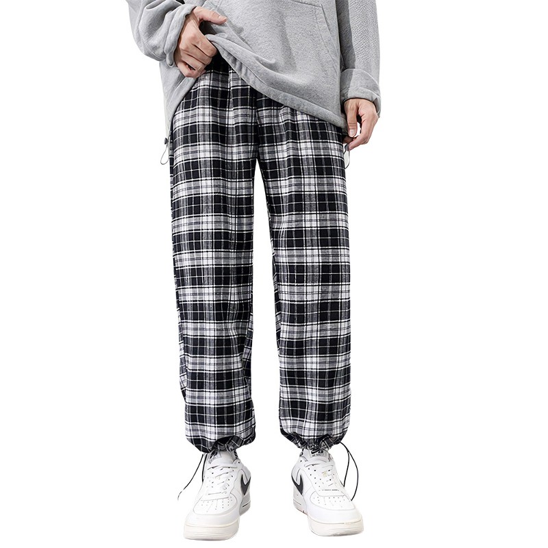 Pantalon écossais à carreaux noir et blanc avec bas resserré porté avec sweat gris et baskets blanches