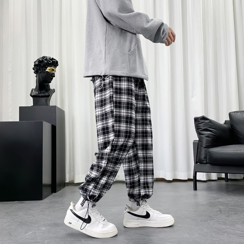 Pantalon écossais à carreaux noir et blanc porté, coupe ample avec bas resserré, motif tartan visible