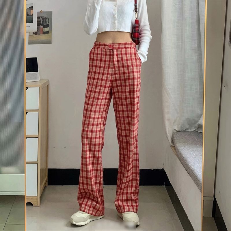 Pantalon écossais coupe droite femme en tissu tartan rouge et beige, porté avec un haut blanc et chaussures blanches
