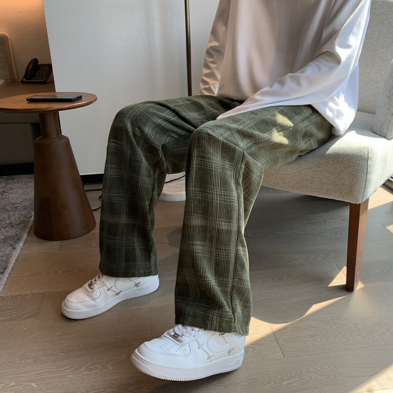 Pantalon écossais large femme vert en tissu tartan assise sur une chaise avec chaussures blanches