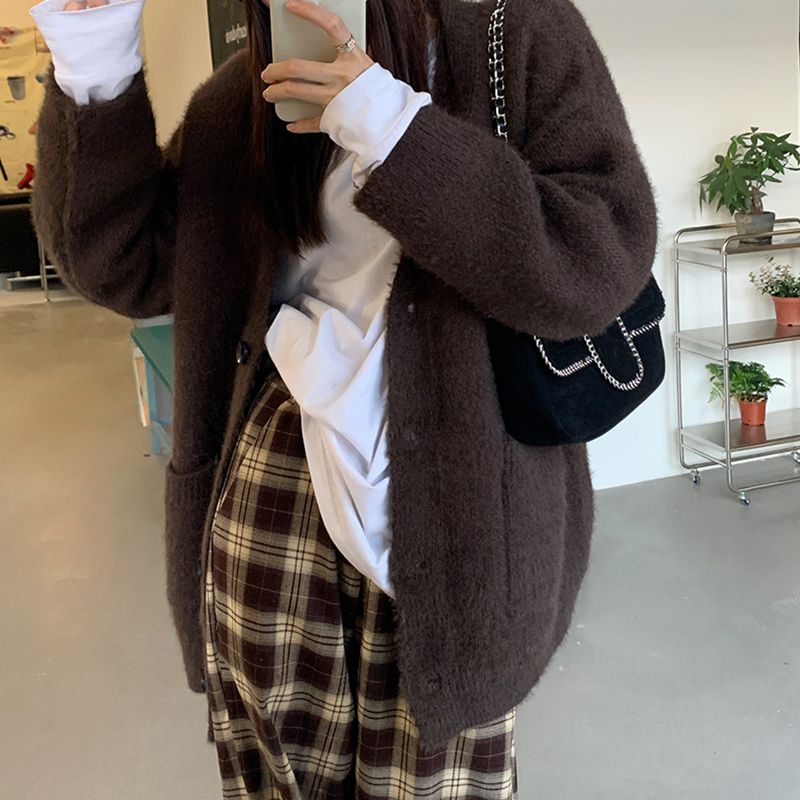 Pantalon large femme à carreaux écossais marron et beige en tissu doux, porté avec un gilet marron oversize et un sac noir à chaîne