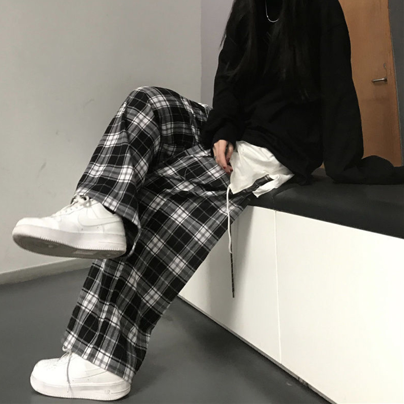 Pantalon large femme à carreaux écossais noir et blanc, porté assis avec baskets blanches