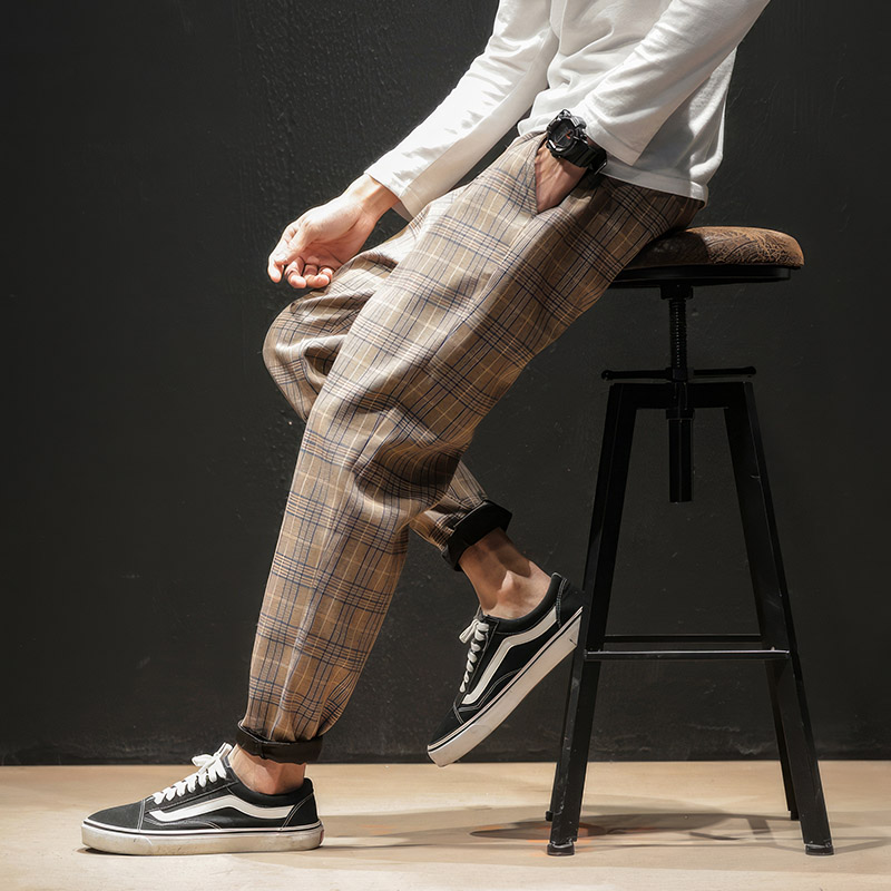 Pantalon tartan beige homme en tissu à motif écossais, coupe décontractée avec bas resserré, porté avec baskets noires et blanches