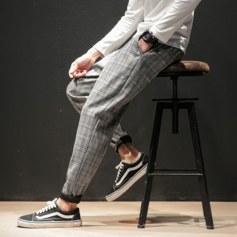 Pantalon tartan gris homme coupe ajustée avec poches latérales et bas resserré porté assis sur un tabouret