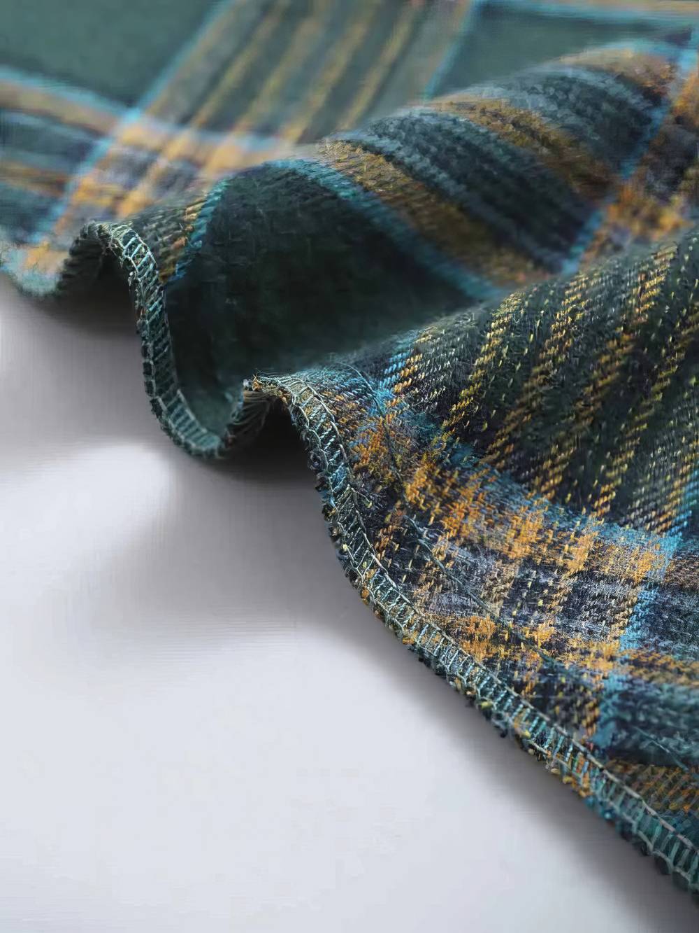 Détail de la bordure roulottée d'une robe écossaise vintage à carreaux vert et beige en tissu tartan