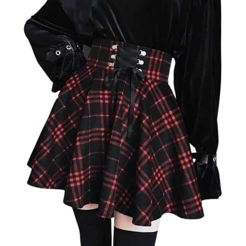 Jupe écossaise courte en tissu tartan rouge et noir avec ceinture à lacets noirs portée avec un haut noir à manches longues