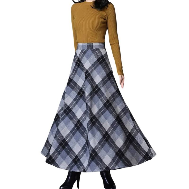 Jupe longue évasée écossaise en tissu gris et noir à motif tartan portée avec un pull marron