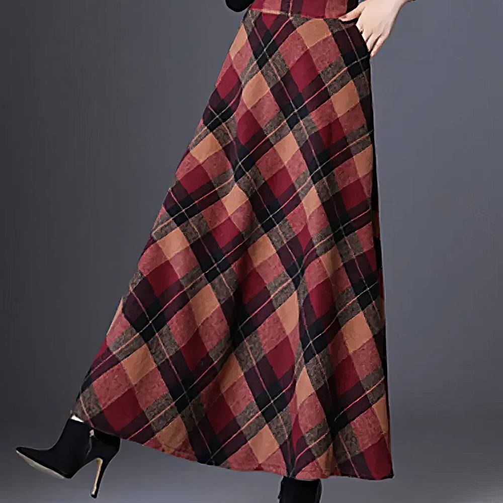 Jupe longue évasée écossaise rouge et beige en tissu tartan, vue de côté sur mannequin avec bottines noires à talons