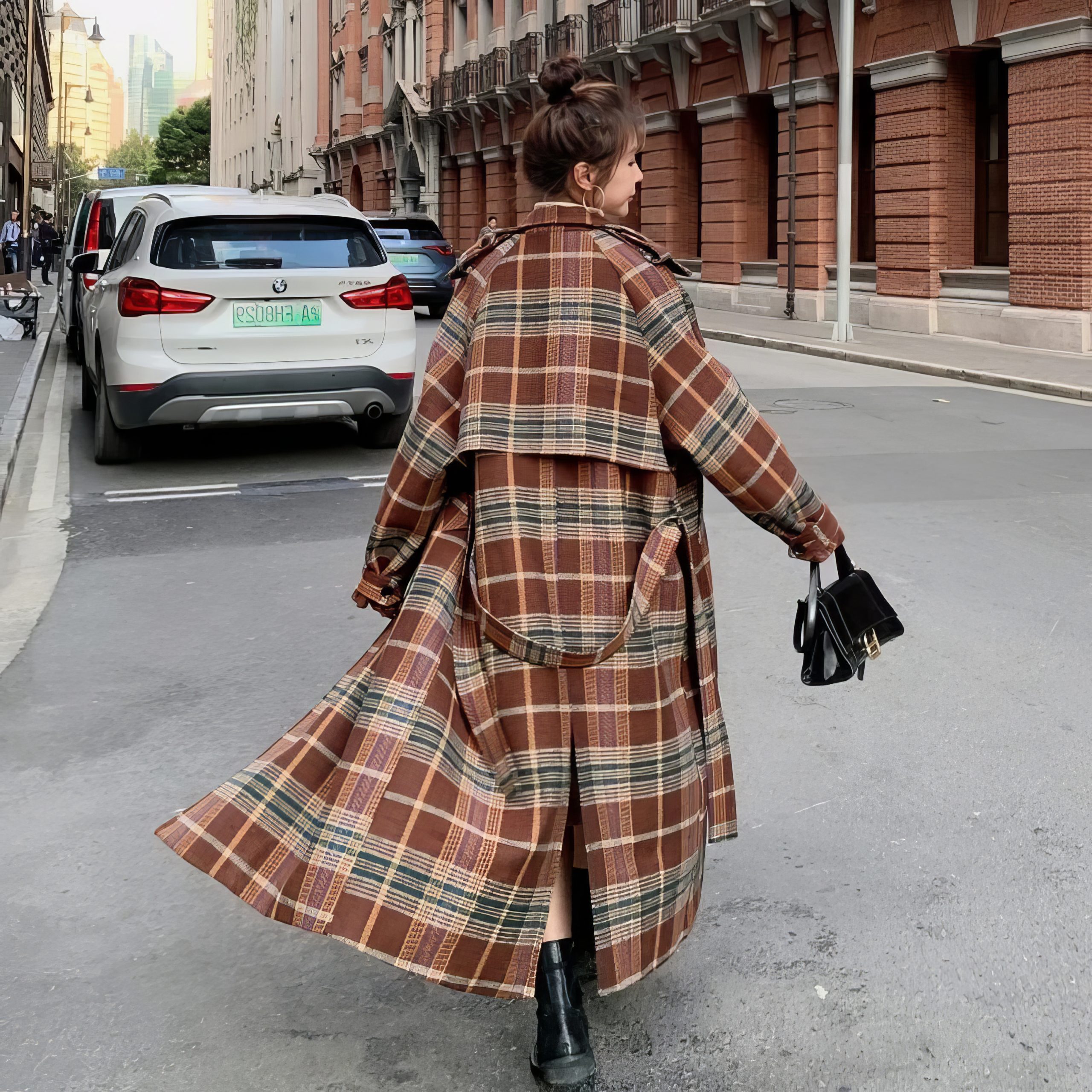 Manteau long écossais à carreaux marron et beige avec ceinture vu de dos en mouvement dans la rue