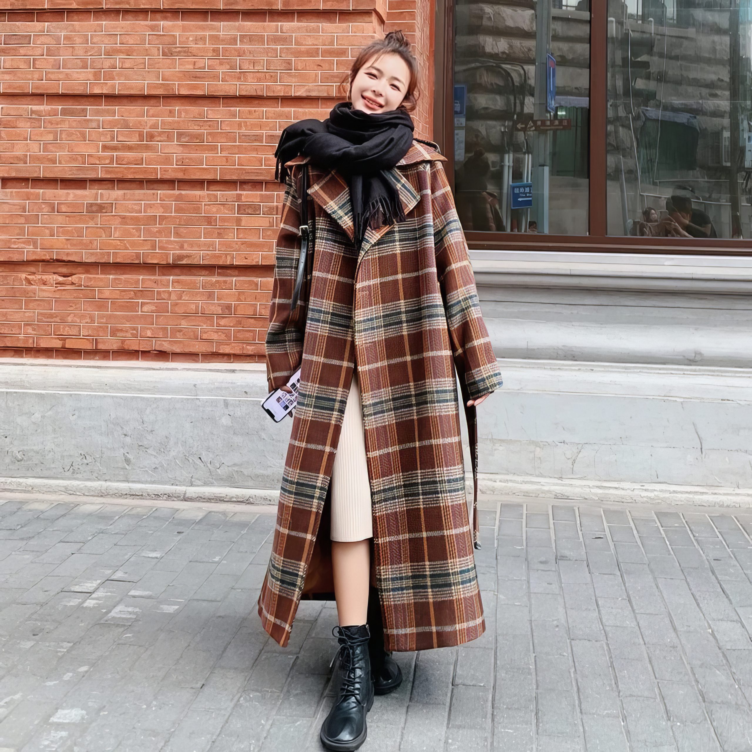 Manteau long écossais à carreaux marron et beige avec ceinture, porté par une femme en extérieur