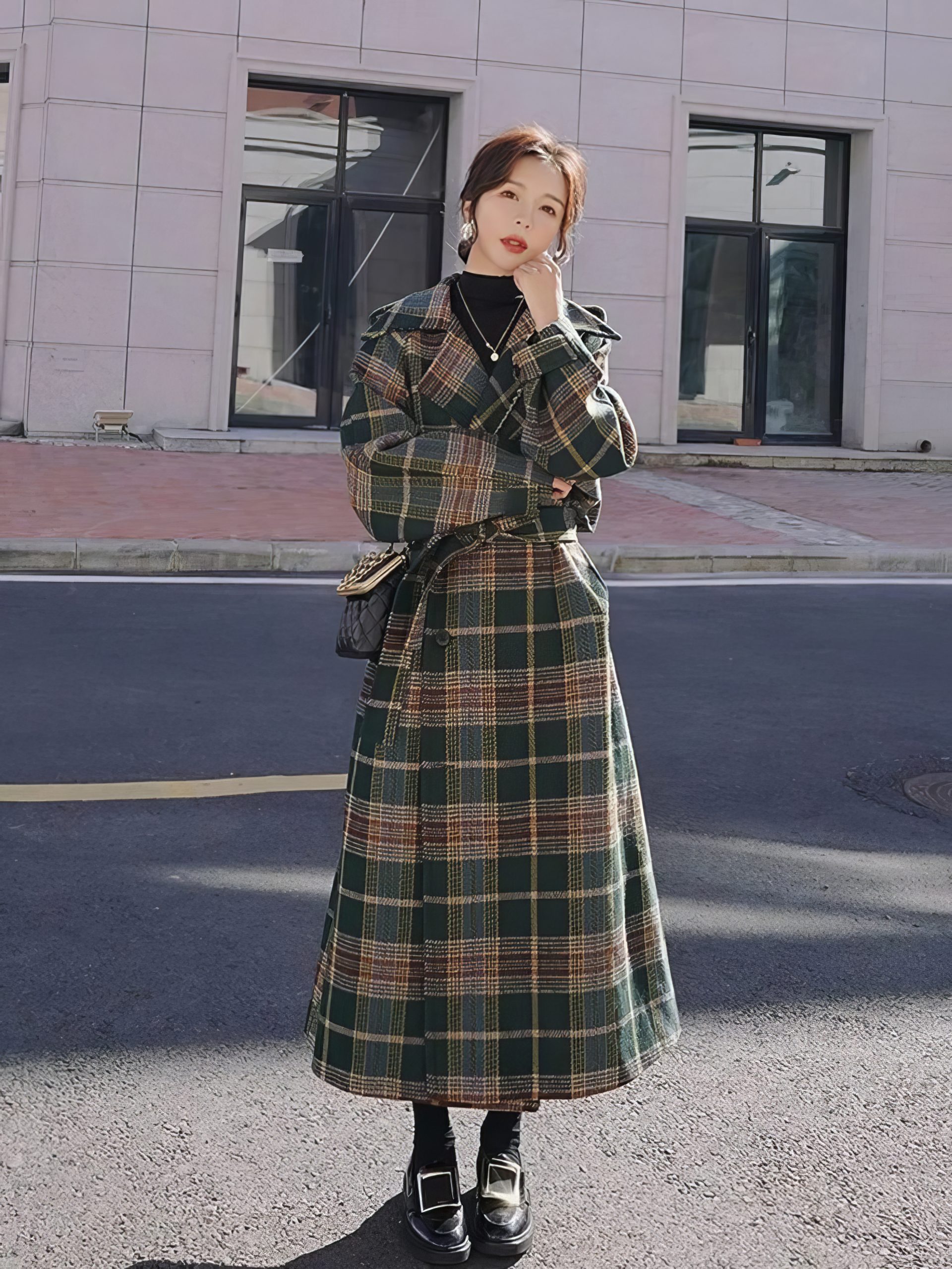 Manteau long écossais à carreaux vert et beige avec ceinture, porté en extérieur, vue de face en pied