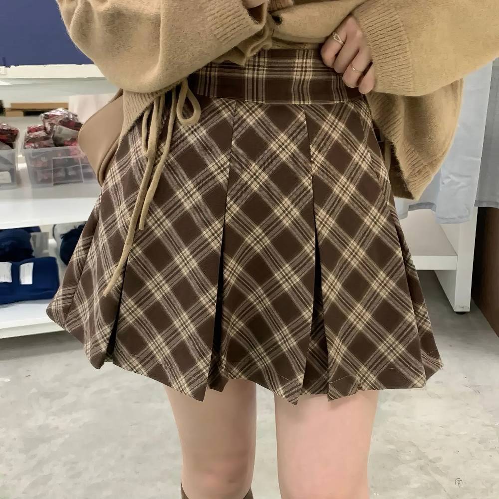 Mini jupe plissée tartan écossaise marron et beige portée de face avec détail des plis et motif à carreaux