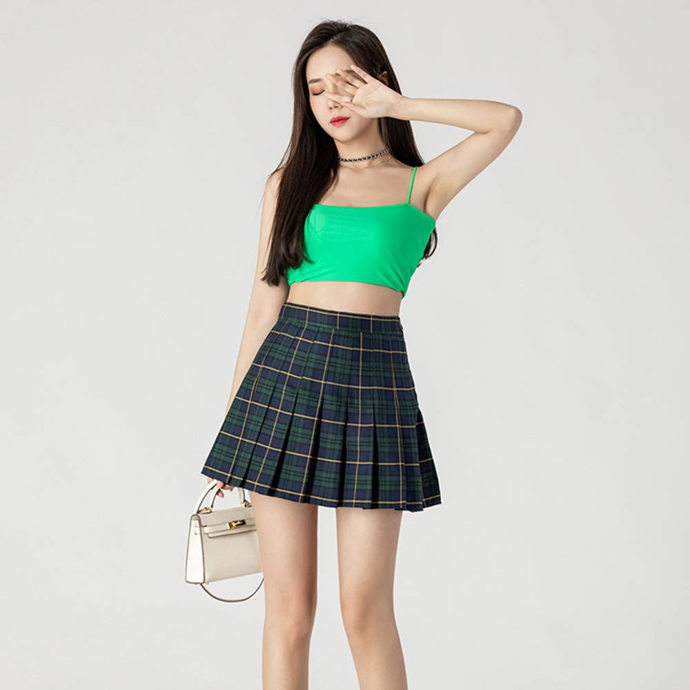 Mini jupe plissée en tartan vert et bleu portée par un mannequin, vue de face avec détail des plis et motif écossais