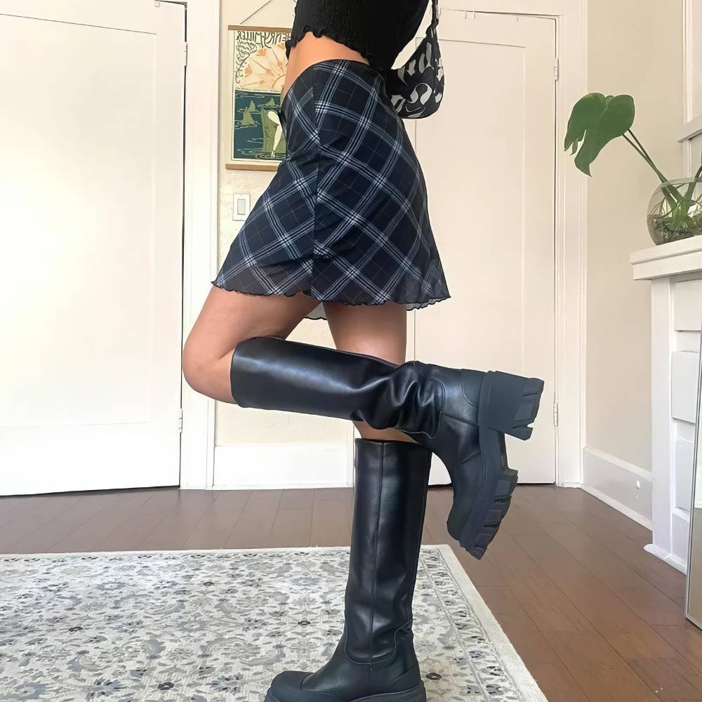 Mini jupe tartan ajustée bleu et noir portée vue de profil avec bottes noires hautes à semelle épaisse