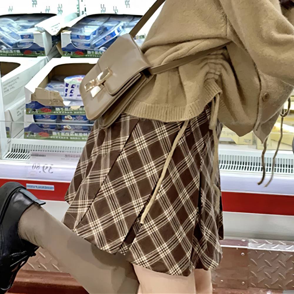 Mini jupe tartan écossaise plissée marron et beige portée vue de côté avec détail plis et motif à carreaux
