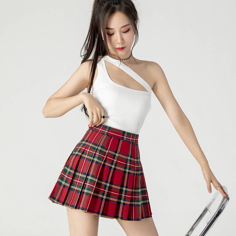 Mini jupe tartan plissée rouge et vert portée par une femme, vue de face avec légère inclinaison, motif écossais classique