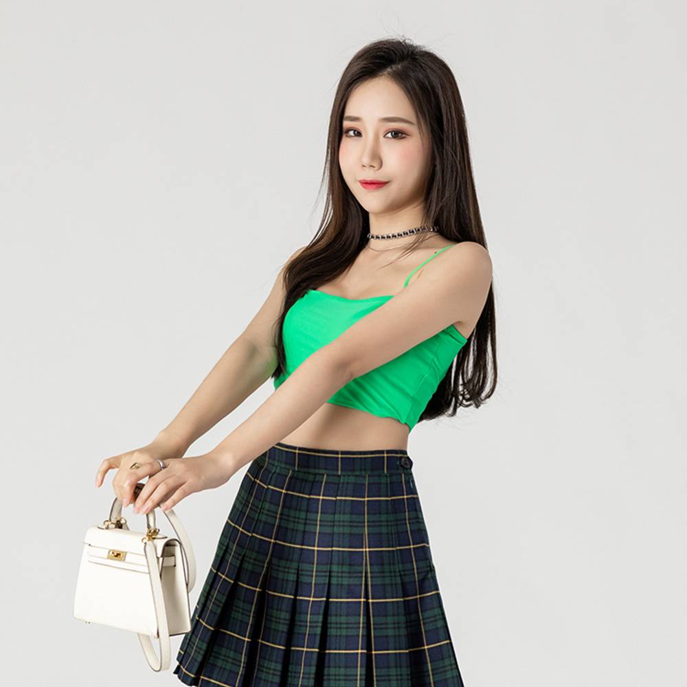 Mini jupe tartan plissée vert et bleu portée vue de face avec détails du plissé et motif écossais