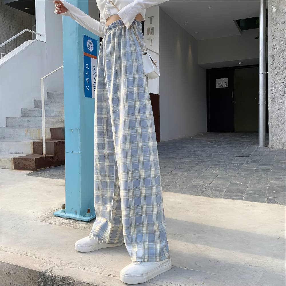 Pantalon écossais femme urbain bleu et blanc à motif tartan, coupe large et taille haute, porté avec des baskets blanches