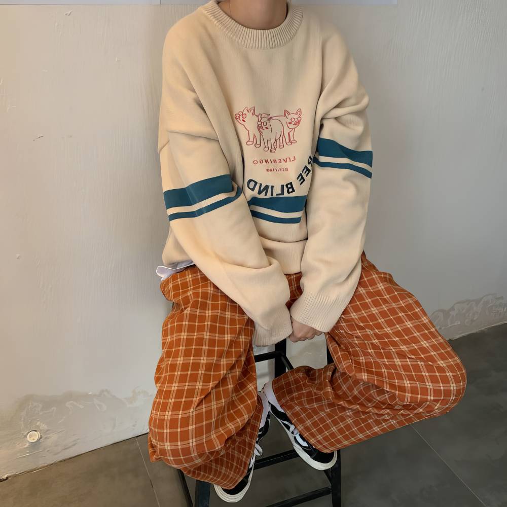 Pantalon écossais large femme orange et beige à carreaux, assise sur un tabouret