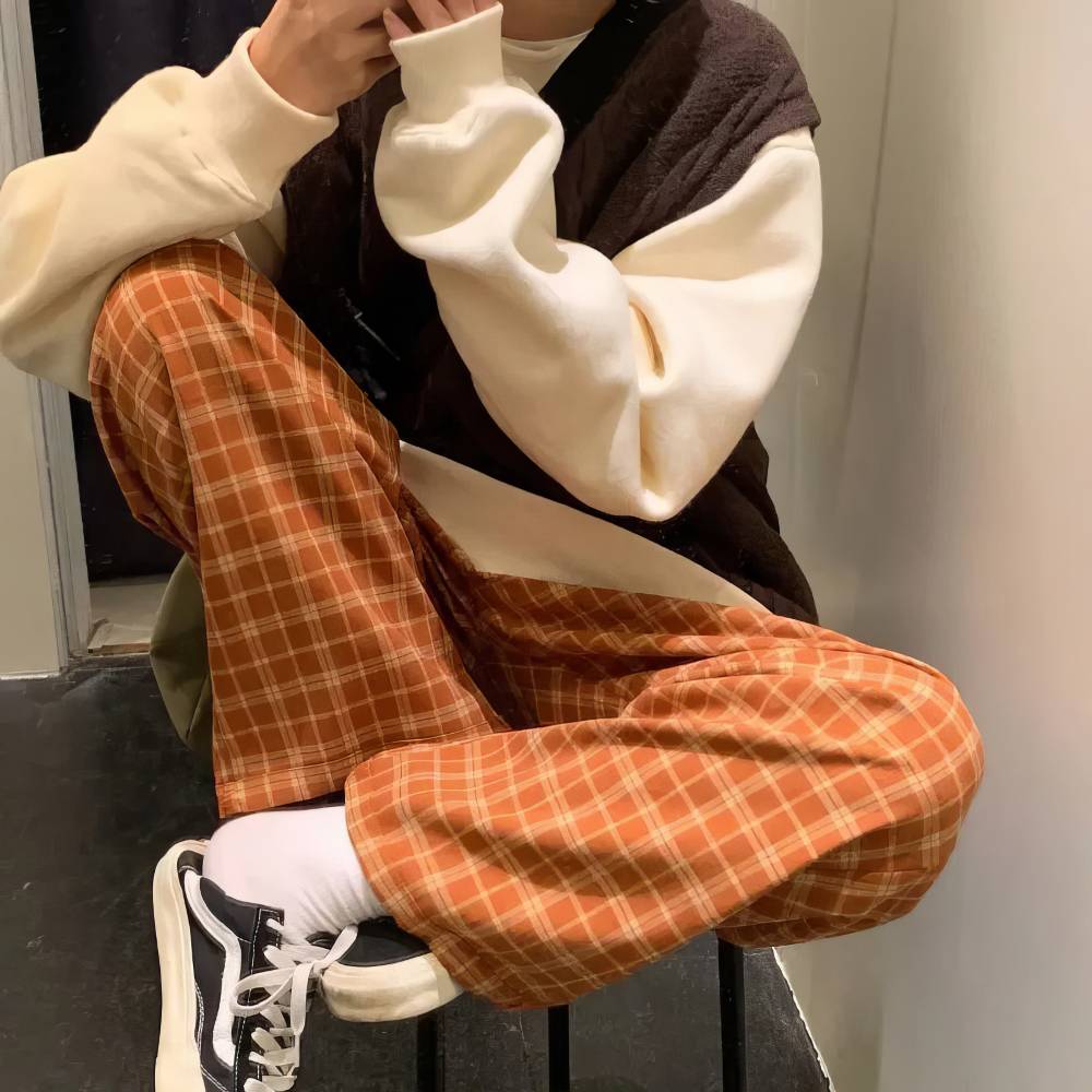 Pantalon écossais large femme orange et beige avec motif tartan, vu en position assise, détail du tissu et coupe ample