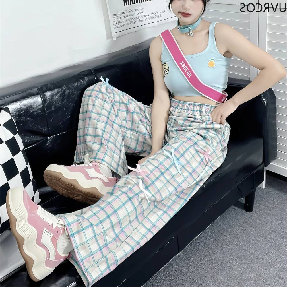 Pantalon écossais Lolita bleu pastel et rose à carreaux, coupe large, porté assis sur un canapé noir