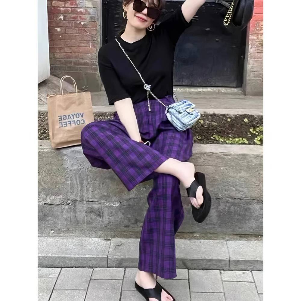 Femme assise portant un pantalon écossais violet et noir à motif tartan, coupe droite, style casual chic