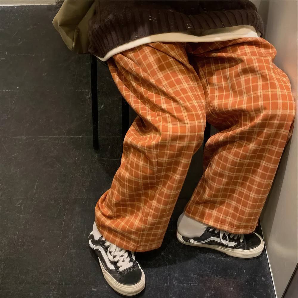 Pantalon large femme motif écossais orange et beige en tissu doux, vue rapprochée sur la coupe ample et le tombé du bas du pantalon