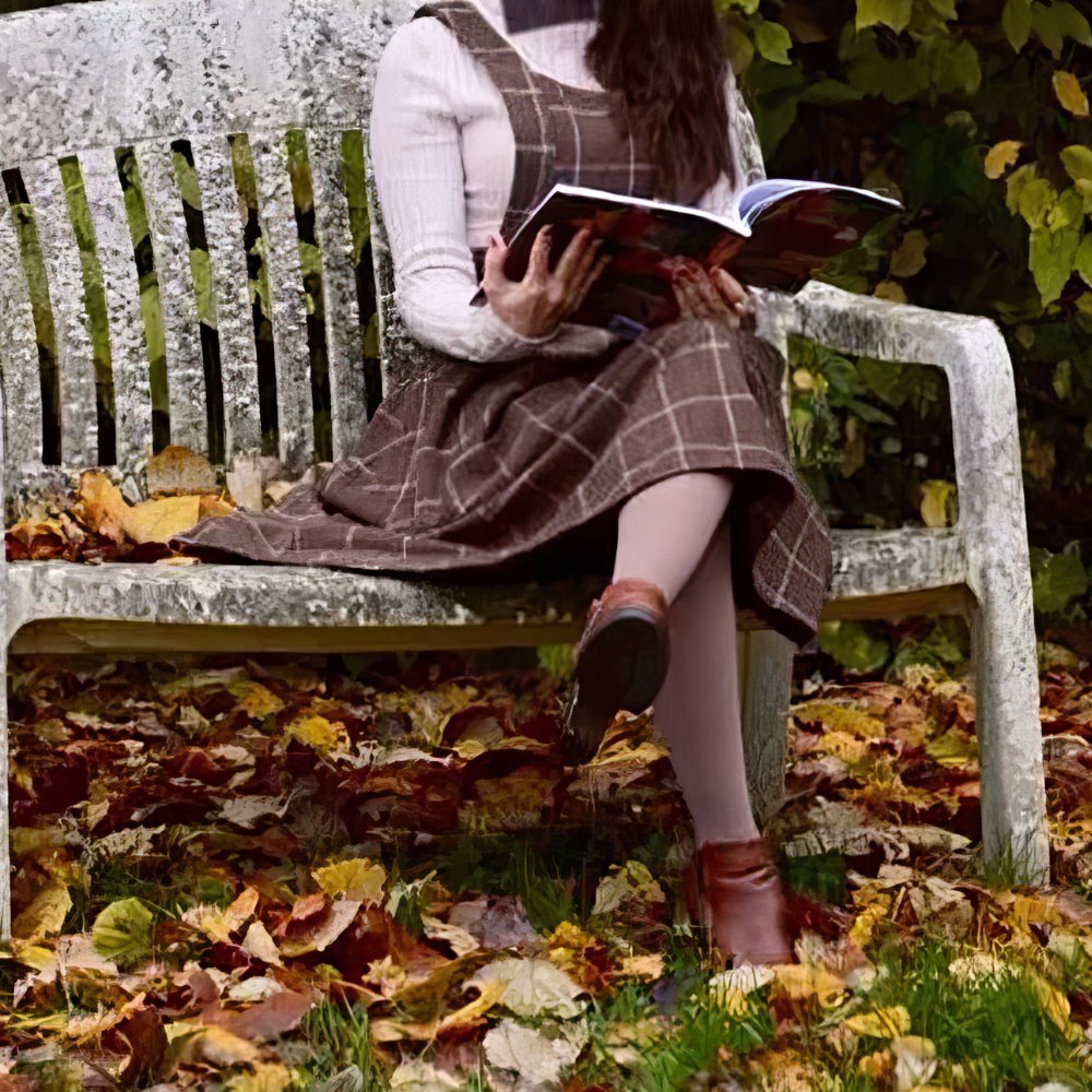 Robe écossaise chasuble marron à motif tartan avec ceinture, portée assise sur un banc en bois dans un parc automnal