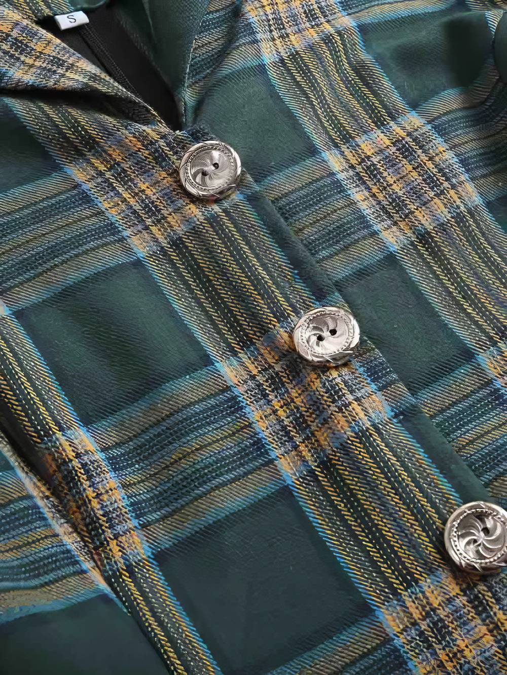 Détail de la robe écossaise vintage à carreaux vert et beige avec boutons argentés gravés